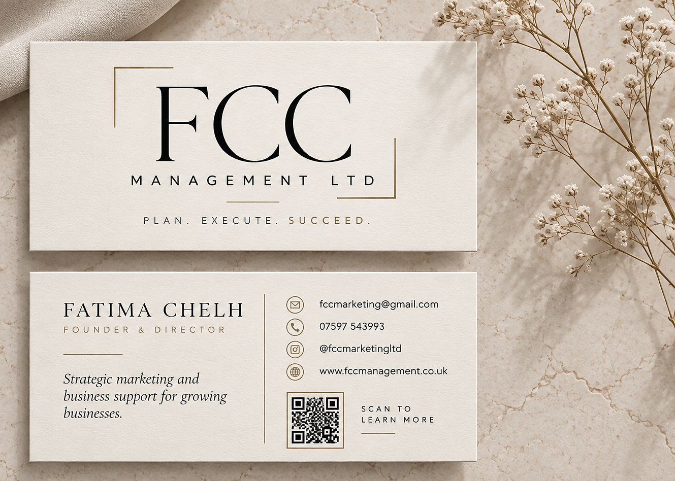 FCC Management business cards on a marble surface beside dried gypsophila